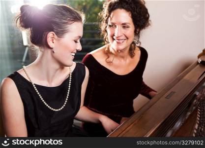 A portrait of a happy mother and daughter playing piano together