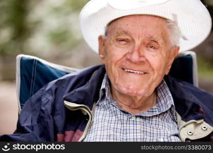 A portrait of a happy smiling elderly man sitting outdoors