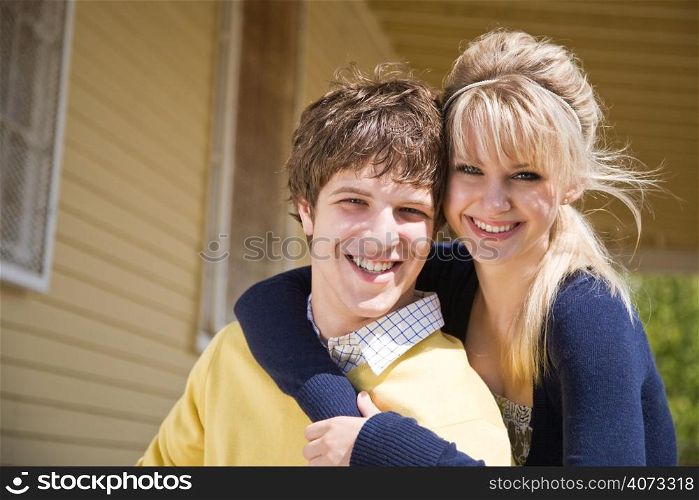 A portrait of a happy young caucasian couple in front of their house