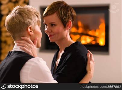 A portrait of a lesbian couple in love, fireplace on background, horizon format
