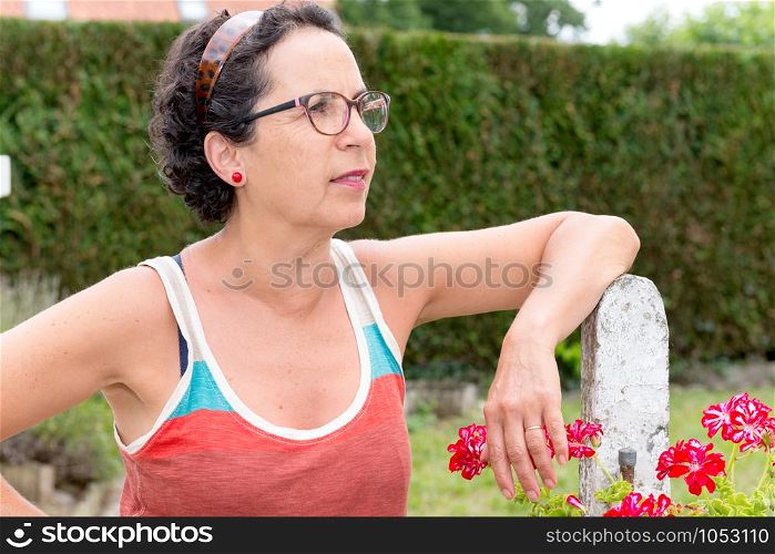 a portrait of a middle-aged brunette woman with eyeglasses, outdoor