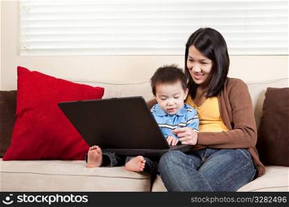 A portrait of a mother and a son using a laptop