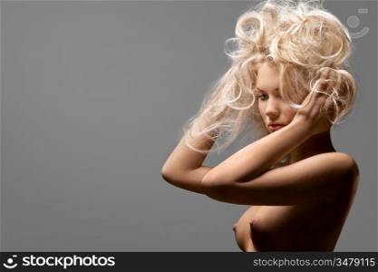 A portrait of a nude sexy blonde with wild hair.