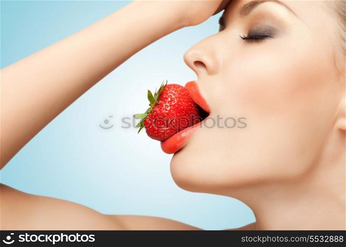A portrait of a nude sexy woman holding a red-ripe strawberry in her mouth.