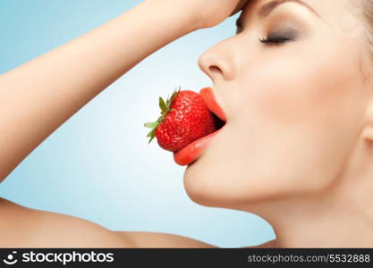 A portrait of a nude sexy woman holding a red-ripe strawberry in her mouth.