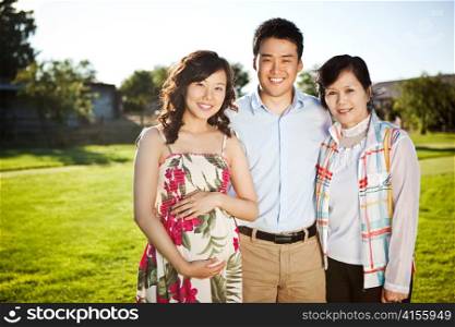 A portrait of a pregnant asian woman with her husband and her mother outdoor