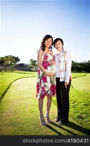 A portrait of a pregnant asian woman with her mother outdoor