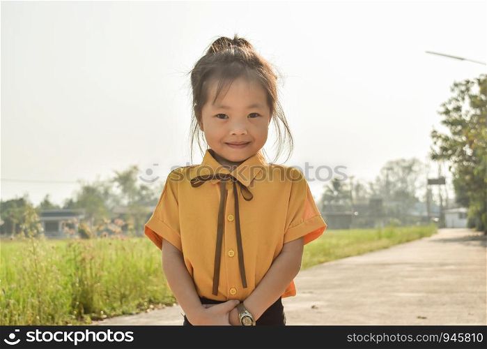 A portrait of a pretty preschool girl Asian against with shy smile.