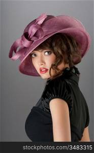 A portrait of a sexy hot brunette with curly hair wearing a beautiful stylish hat.