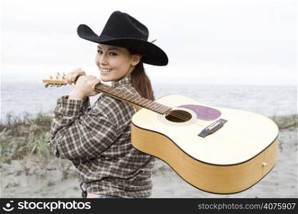 A portrait of a smiling beautiful cowgirl carrying a guitar
