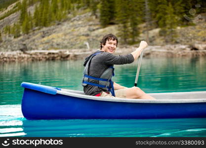 A portrait of a smiling man in a canoe on a glacial lake