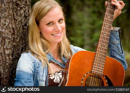 A portrait of a woman holding a guitar in an outdoor setting