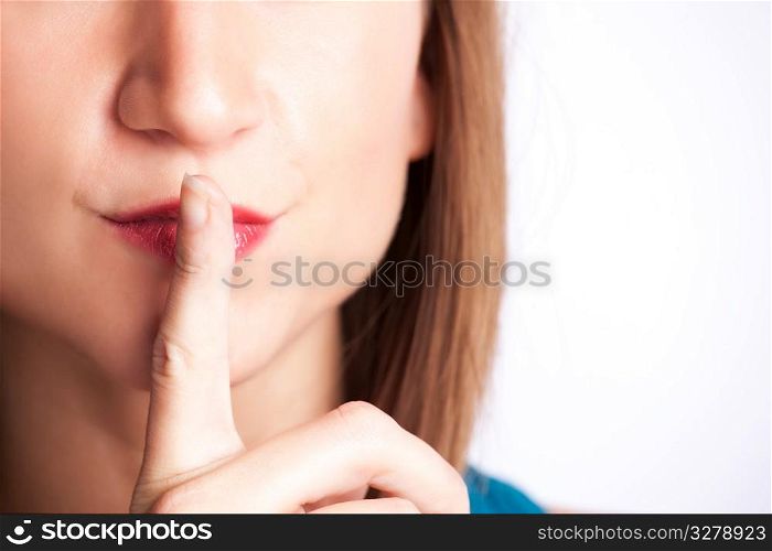 A portrait of a woman shushing with her finger on her lips