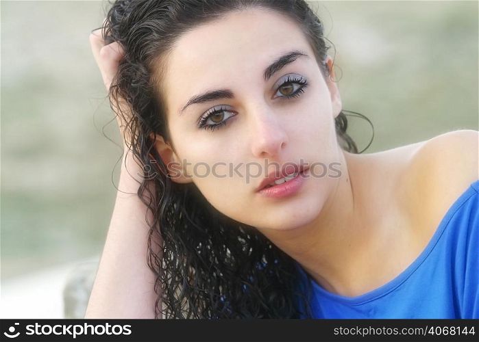 A portrait of a woman with wet curly hair wearing a blue top.