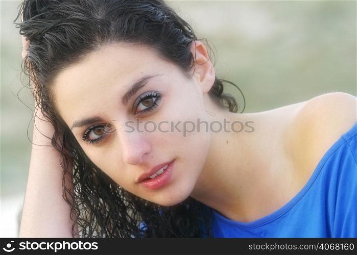 A portrait of a woman with wet curly hair wearing a blue top.