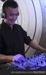 A portrait of a young male DJ playing music in a nightclub