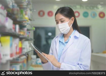 A portrait of asian woman pharmacist wearing a surgical mask in a modern pharmacy drugstore, covid-19 and pandemic concept.. Portrait of asian woman pharmacist wearing a surgical mask in a modern pharmacy drugstore, covid-19 and pandemic concept.