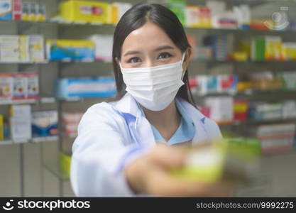 A portrait of asian woman pharmacist wearing a surgical mask in a modern pharmacy drugstore, covid-19 and pandemic concept.. Portrait of asian woman pharmacist wearing a surgical mask in a modern pharmacy drugstore, covid-19 and pandemic concept.