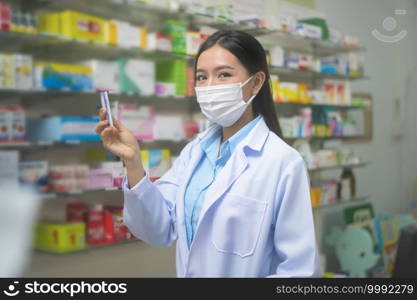 A portrait of asian woman pharmacist wearing a surgical mask in a modern pharmacy drugstore, covid-19 and pandemic concept.. Portrait of asian woman pharmacist wearing a surgical mask in a modern pharmacy drugstore, covid-19 and pandemic concept.