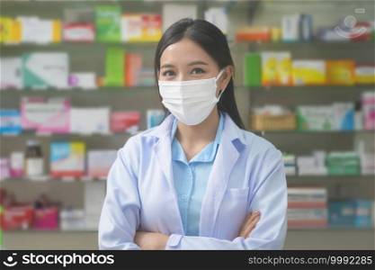 A portrait of asian woman pharmacist wearing a surgical mask in a modern pharmacy drugstore, covid-19 and pandemic concept.. Portrait of asian woman pharmacist wearing a surgical mask in a modern pharmacy drugstore, covid-19 and pandemic concept.