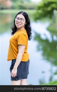 a portrait of beautiful happy asian woman traveler wearing yellow orange dress stylish hipster lifestyle on the street outdoors at summer day in park or in background
