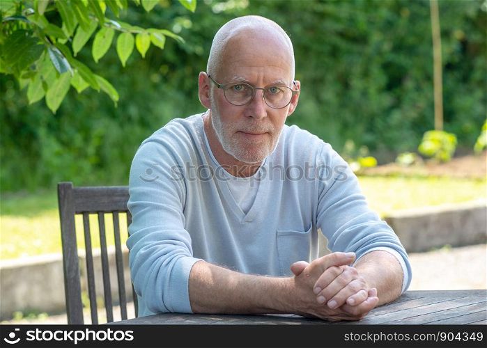 a portrait of senior man with glasses, outdoors