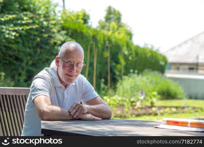 a portrait of senior man with glasses sitting in the garden