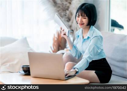 a portrait of Smiling with dental braces of asian freelance people business female written Notes to on notebook working with laptop computer with coffee cup and smartphone in coffee shop