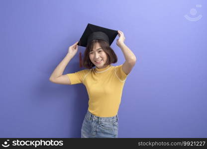 A portrait of young Asian student wearing graduation cap over studio background.. Portrait of young Asian student wearing graduation cap over studio background.