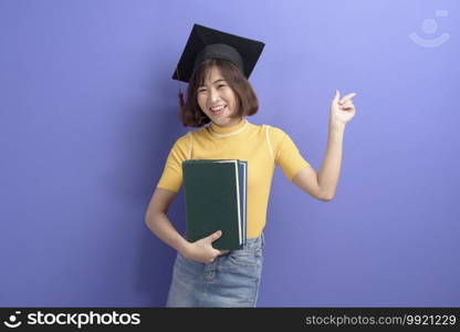 A portrait of young Asian student wearing graduation cap over studio background.. Portrait of young Asian student wearing graduation cap over studio background.