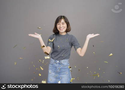A portrait of young beautiful asian woman celebrating and playing paper shoot isolated gray background studio, Christmas and New Year Concept.. Portrait of young beautiful asian woman celebrating and playing paper shoot isolated gray background studio, Christmas and New Year Concept.