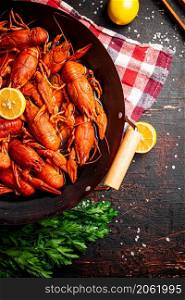 A pot of boiled crayfish on a napkin. Against a dark background. High quality photo. A pot of boiled crayfish on a napkin.
