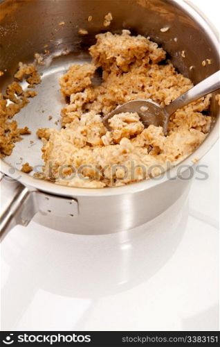 A pot of old cold porridge on a reflective white background