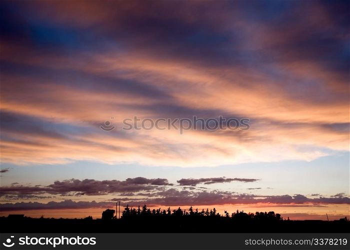 A prairie farm against a dramatic sunset