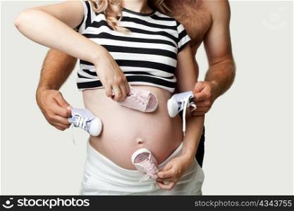 A pregnant woman and her husband with little shoes