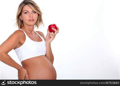A pregnant woman eating an apple.