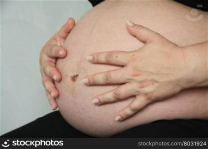 A pregnant woman showing her pregnant tummy, baby is due in three weeks