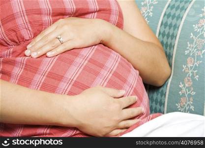 A pregnant woman sitting down on a sofa