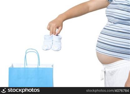 A pregnant woman taking out baby shoes from a shopping bag