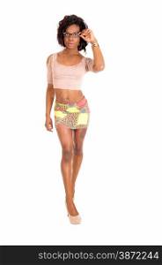 A pretty African American woman in a short skirt a t-shirt and heelsstanding in profile isolated for white background.