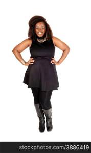 A pretty African American woman standing in a black dress, tights and bootssmiling isolated for white background.