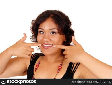 A pretty and smiling mixed raised woman pointing with her fingersat her teeth, isolated for white background.