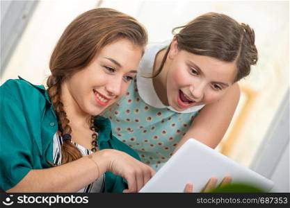 a pretty beautiful charming teen and her older friend using tablet
