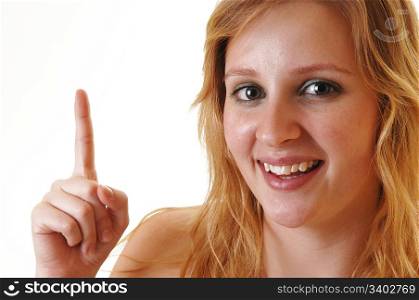 A pretty blond teenager girl, smiling and pointing one finger up, forwhite background.
