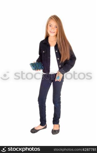 A pretty eight year old girl standing isolated for white background in jeans anda jean jacket, holding her purse.
