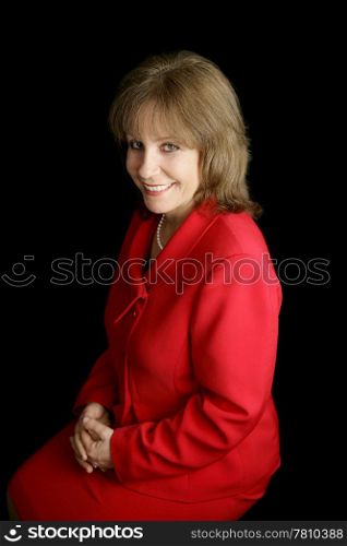 A pretty, friendly woman in a red business suit. Black background.