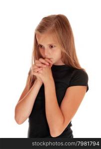 A pretty girl in a black sweater with her hands folded and praying, standingisolated for white background.