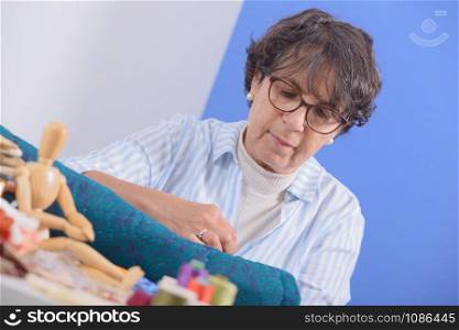 a pretty mature brunette woman sewing patchwork