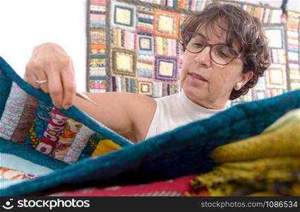 a pretty mature brunette woman sewing patchwork