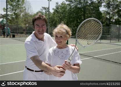A pretty senior lady on the courts with a tennis pro.